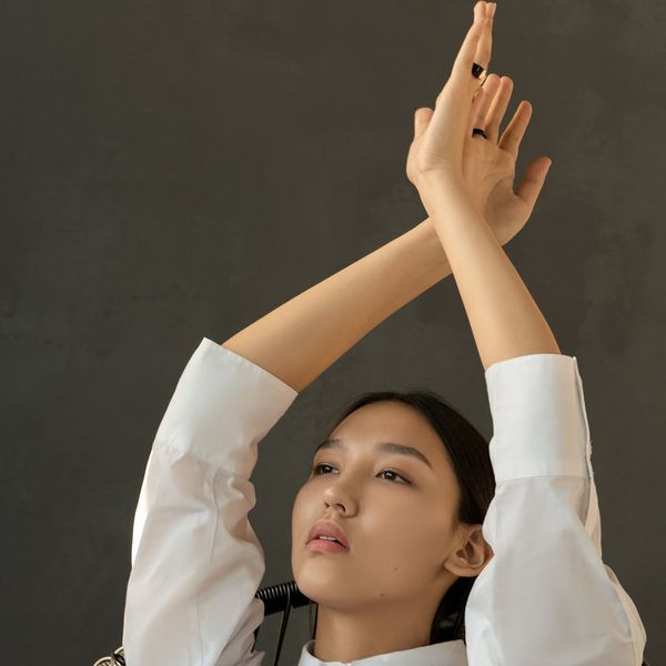 Woman in a serene yoga pose against a dark, minimalist background.